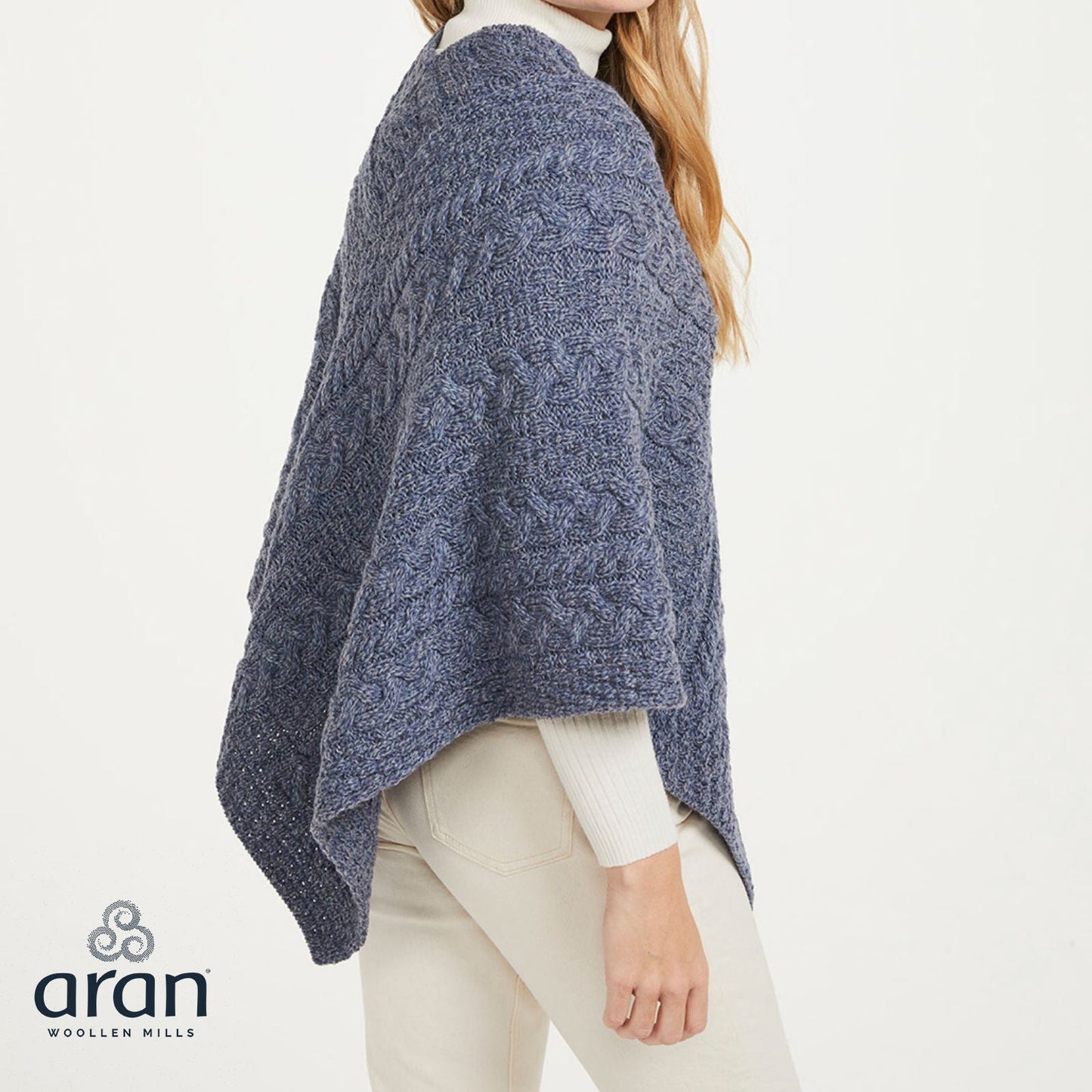 Side view of a blue denim Aran knit poncho worn over a white turtleneck.