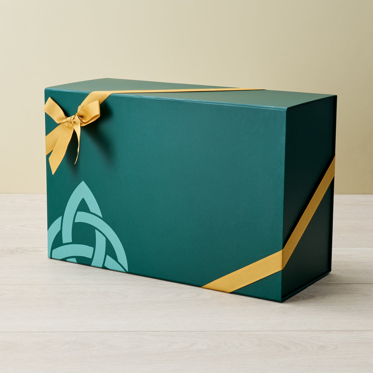 Medium green gift box with teal decorative motif in the corner and a yellow ribbon tied diagonally