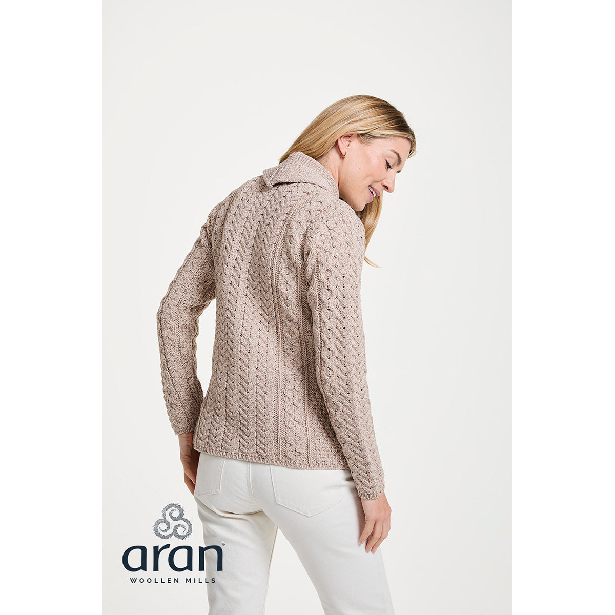 Back view of a taupe knitted cardigan with a textured cable pattern worn by a model against a white studio background.