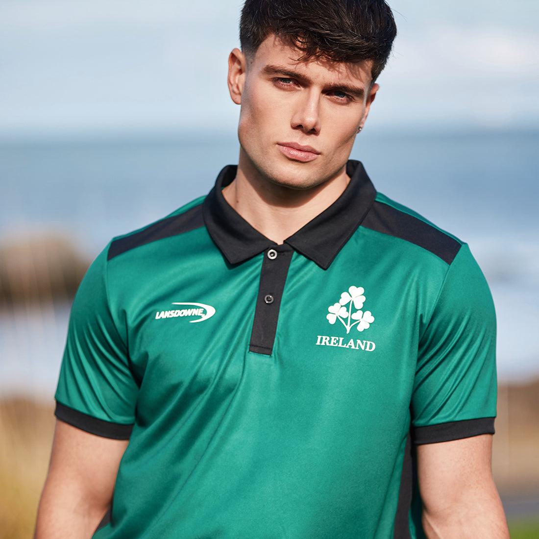 Male model wearing green Ireland polo with black collar and crest and sponsor logo on chest