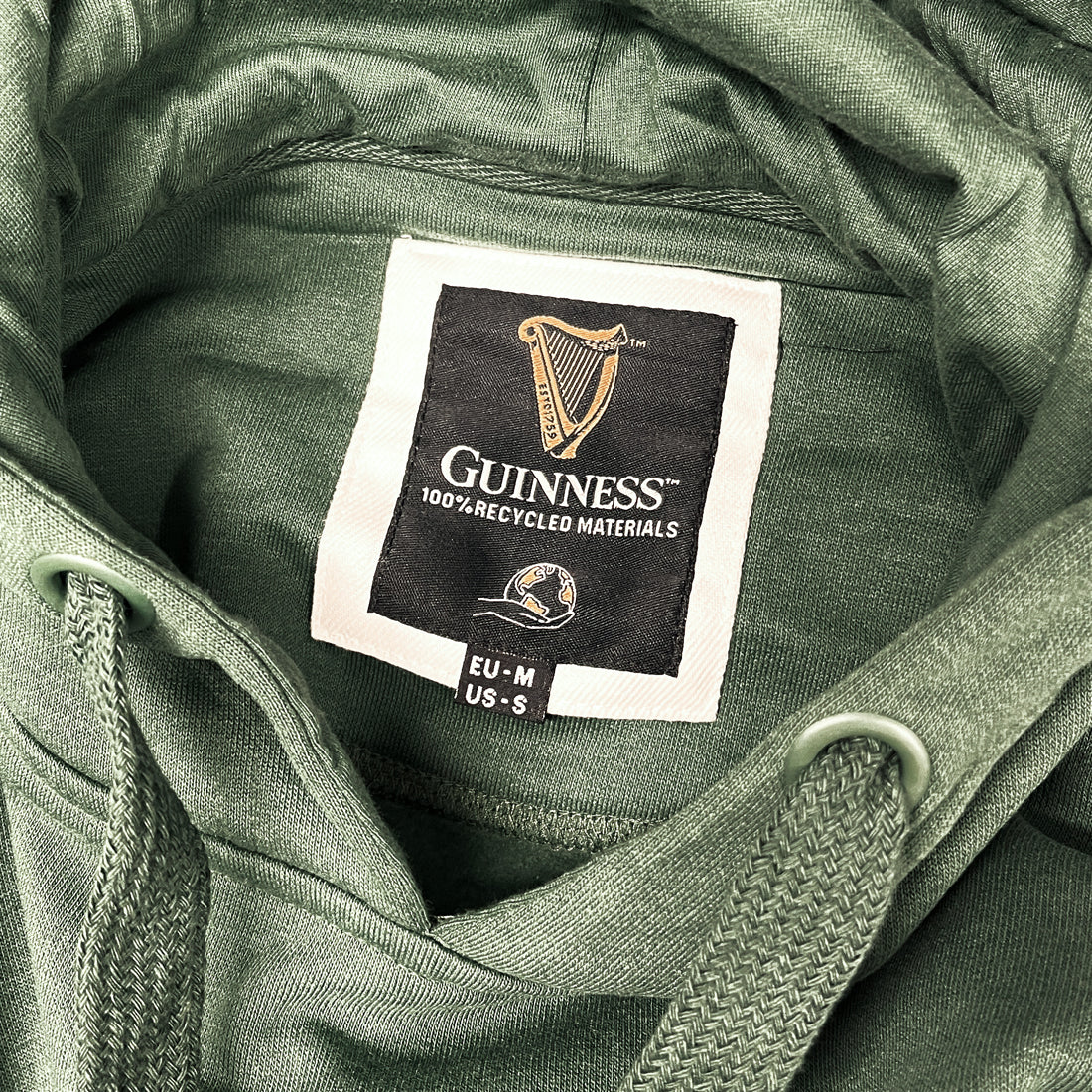 Guinness label inside a green hoodie showing 100% recycled materials