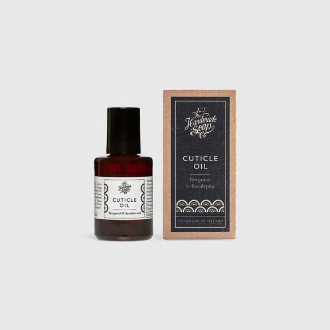 Amber glass bottle of Bergamot and Eucalyptus Cuticle Oil beside a kraft paper box.