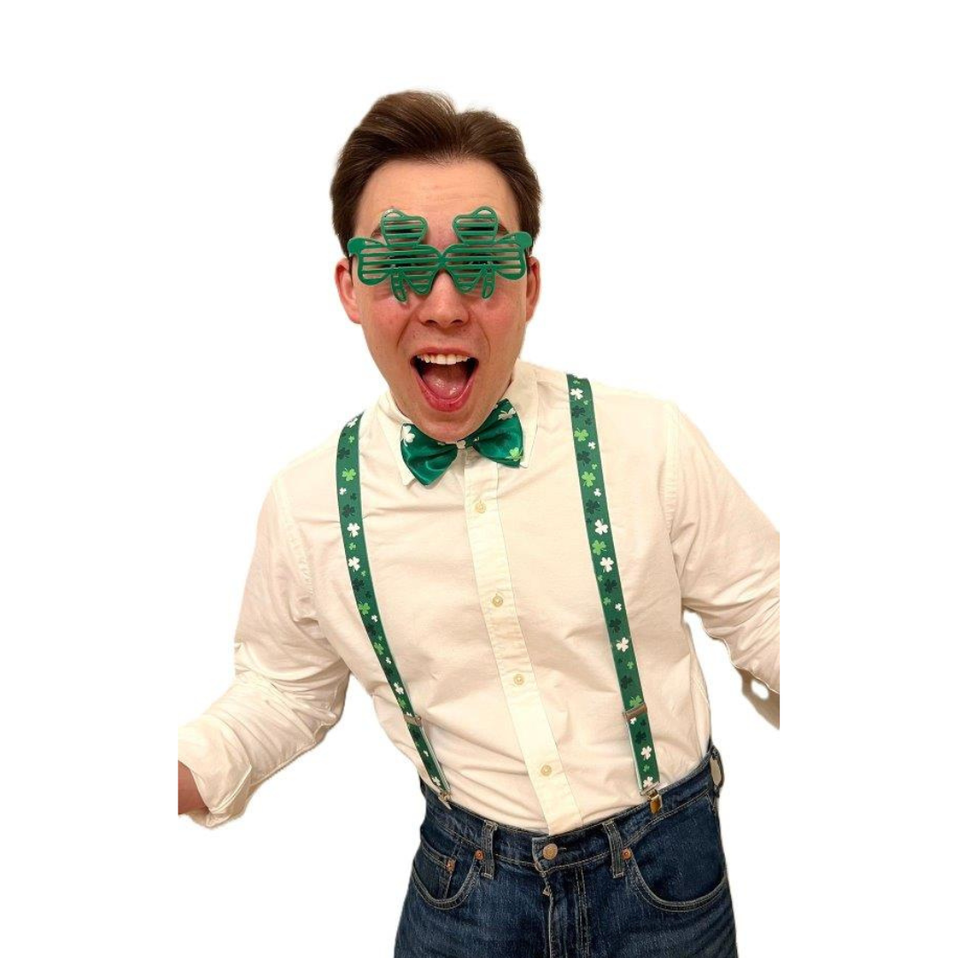 Man wearing shamrock glasses, green bow tie, and suspenders smiling excitedly