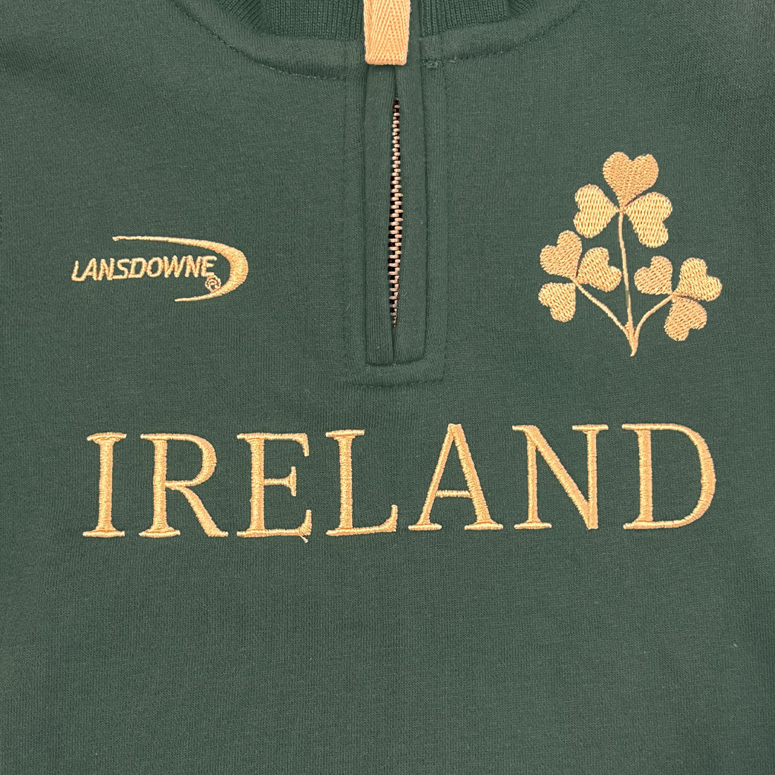 Close up of a green quarter zip top showing Ireland crest embroidery and Lansdowne logo on the chest