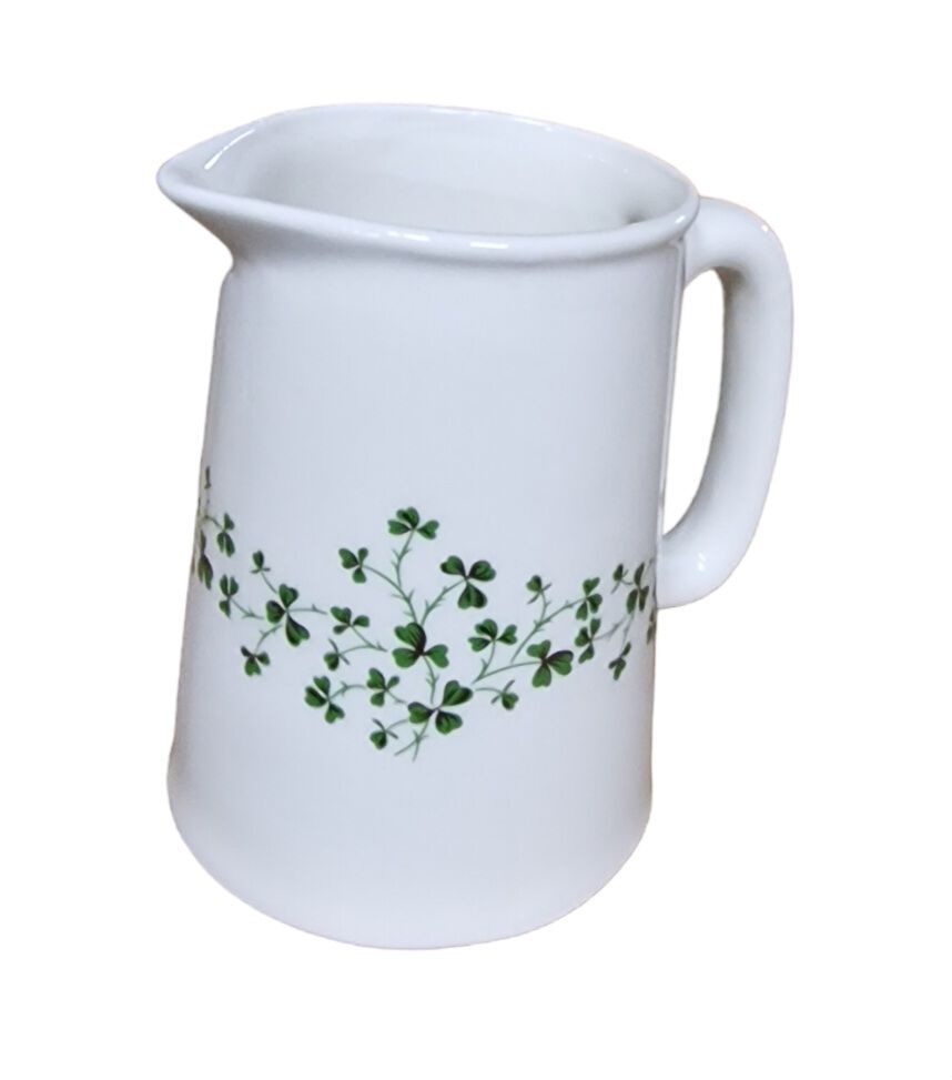 White ceramic pint jug with a green shamrock vine pattern and a curved handle.