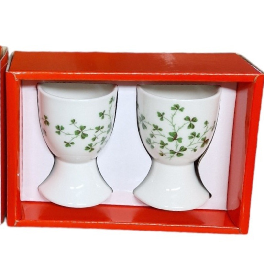 Two white ceramic egg cups with green shamrock pattern in a red gift box.