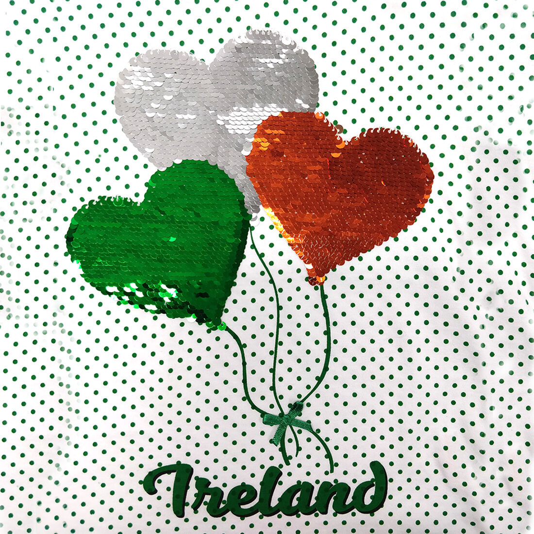 Three heart shaped sequin balloons in green white and orange on a dotted background with Ireland text