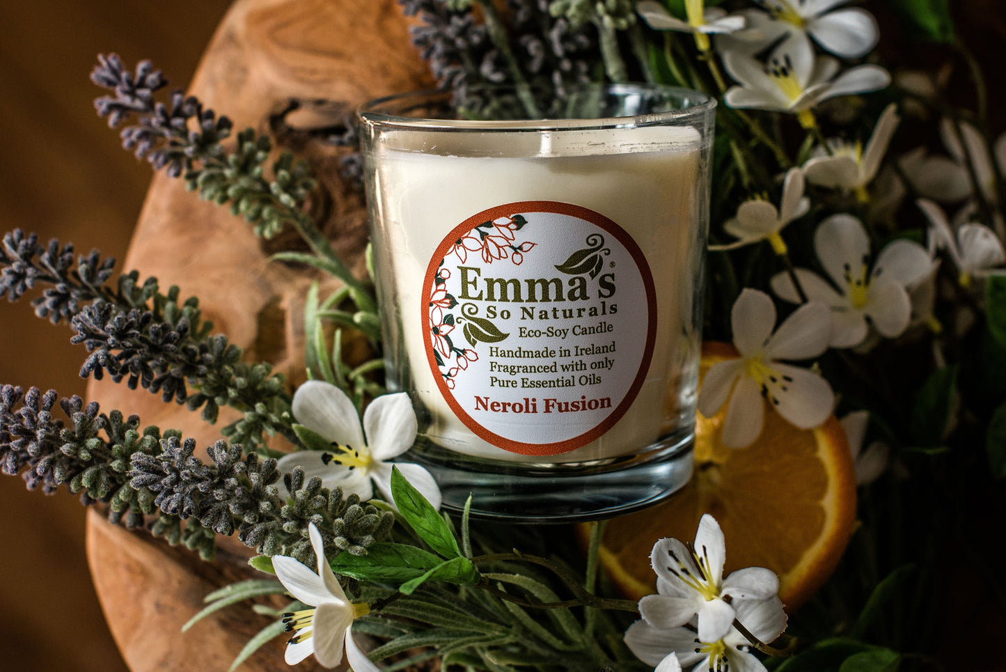Neroli Fusion tumbler candle in a clear glass jar surrounded by lavender sprigs white blossoms and orange slices