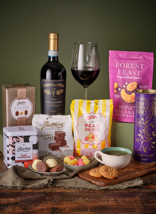 Gourmet Irish Treats Gift Basket with biscuits chocolates jam pear drops and a bottle of red wine.