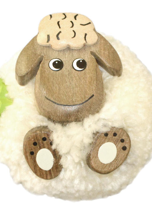 Fluffy white sheep magnet with wooden face and floppy ears sitting on a plush wool base