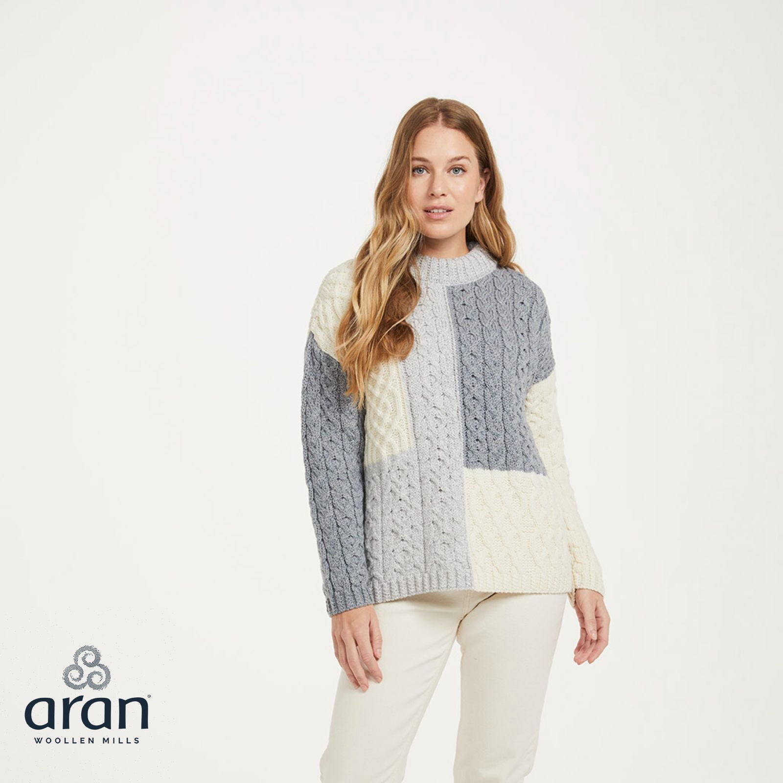 Front view of a model wearing a ladies three color patchwork sweater in grey cream from Aran Woollen Mills
