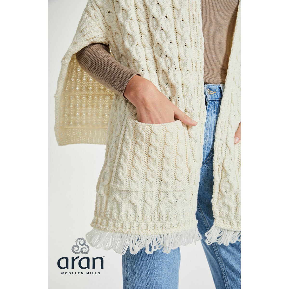 Close up of cream Shannon wrap with hand in pocket, highlighting pocket detail and fringed edge.