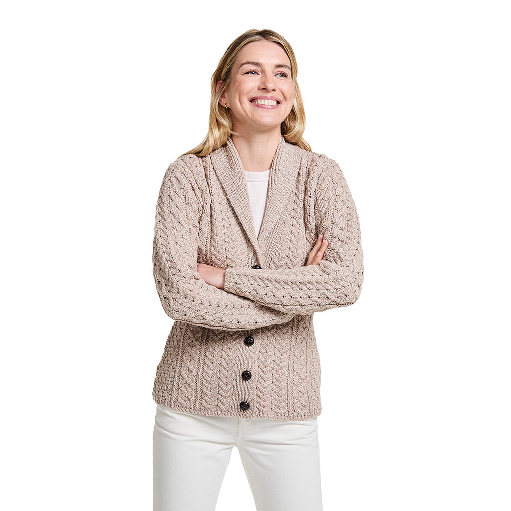 Beige shawl collar Merino Aran cardigan on a smiling model with a chunky knit pattern and button front.