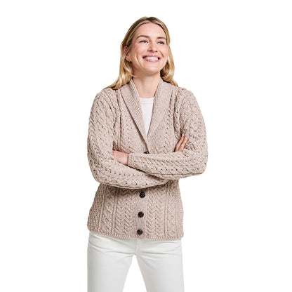 Beige shawl collar Merino Aran cardigan on a smiling model with a chunky knit pattern and button front.
