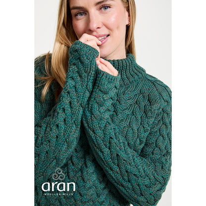 Close up of a model wearing a green Knightstown Merino Aran Crew Sweater with chunky cable knit.