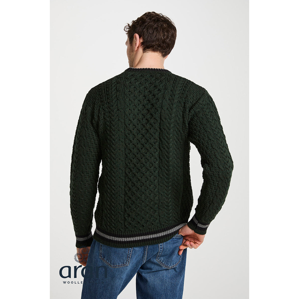 Back view of male model wearing Inishbeg Stripe Crewneck Merino Green Aran Sweater showing cable knit and striped hem