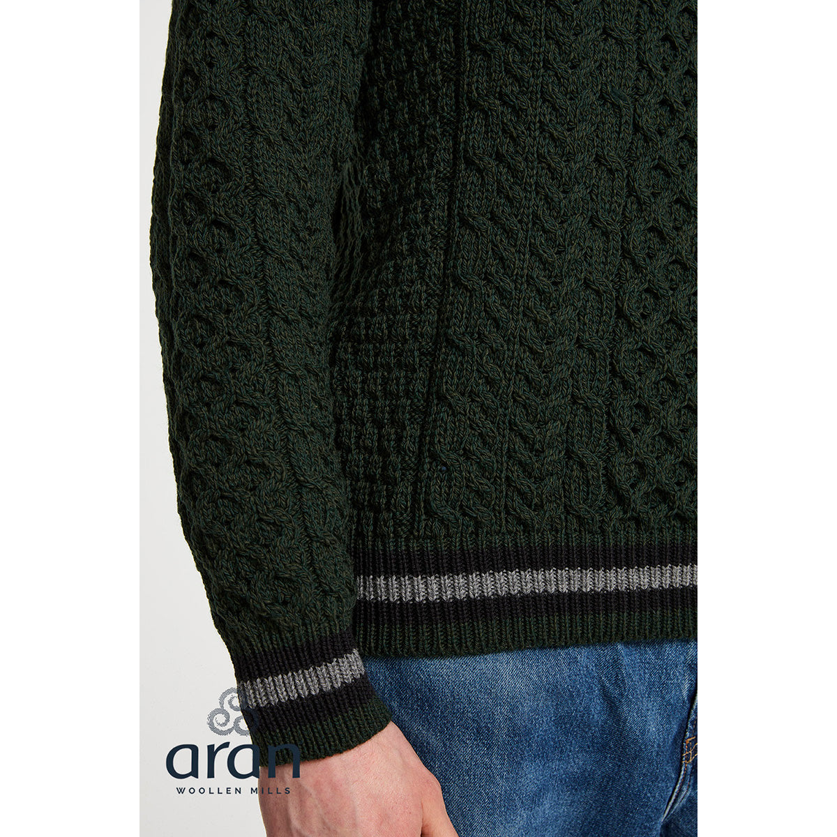 Close up of dark green Aran knit texture with ribbed cuff and gray stripe detail from the Inishbeg sweater