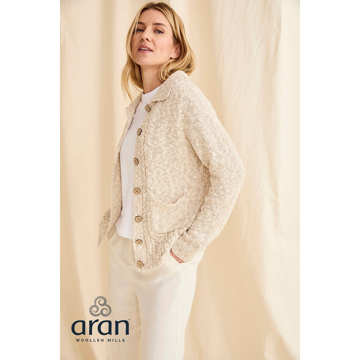 Cream Eriu cardigan worn by a model featuring textured knit, wooden buttons and front pockets.