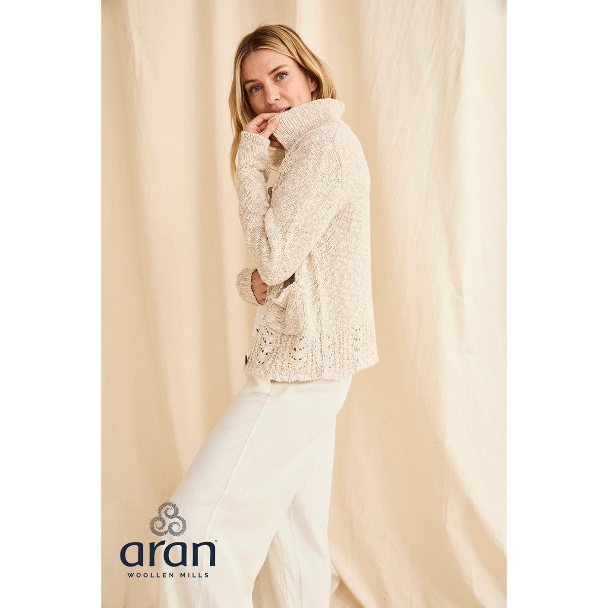 Model in cream Eriu cardigan from the side, showing a textured knit and lace hem detail.