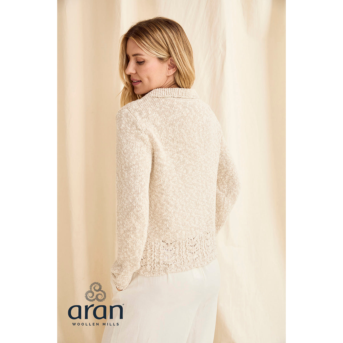 Back view of cream Eriu cardigan with textured knit and decorative lace hem.