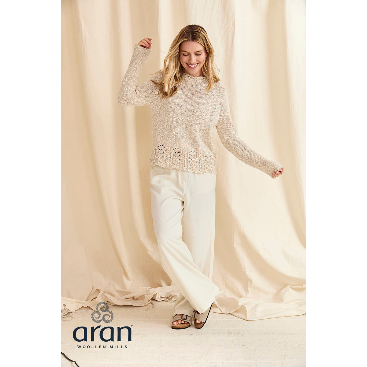 Model wearing cream Arawn cotton linen crew sweater with textured knit and decorative lace hem.