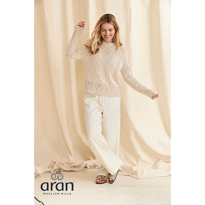 Model wearing cream Arawn cotton linen crew sweater with textured knit and decorative lace hem.