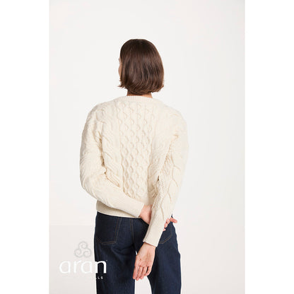 Back view of a cream cropped cable knit sweater worn by a model