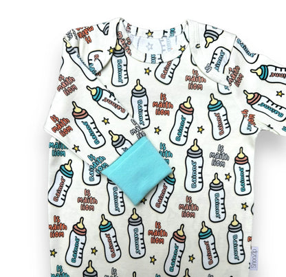 White Snoozip Bainne baby onesie with colorful bottle print and turquoise cuffs laid flat