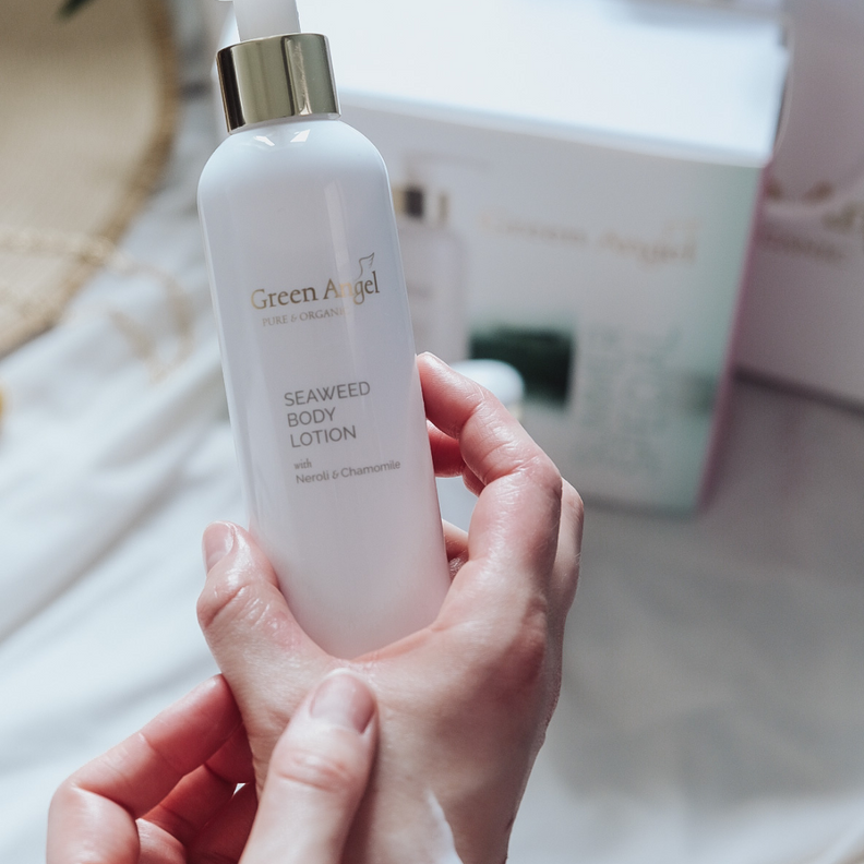 Green Angel Seaweed Body Lotion bottle with pump held in hands with the packaging box in the background.