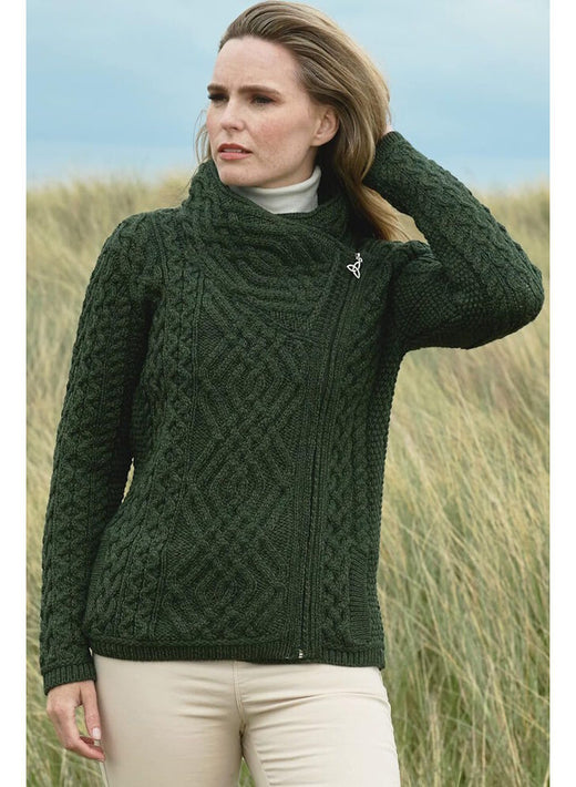 Woman wearing dark green cable knit sweater standing outdoors in grassy area