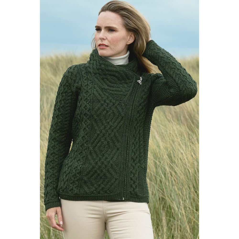 Woman wearing dark green cable knit sweater standing outdoors in grassy area