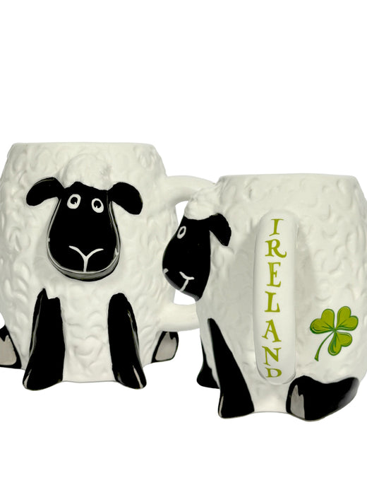 Pair of white sheep shaped ceramic mugs with textured wool and black faces, one with IRELAND lettering and green shamrock.