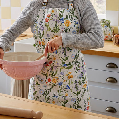 Cottage Garden Cotton Apron worn in a kitchen, person stirring in a pink mixing bowl