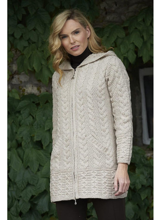 Woman wearing a beige knitted hooded cardigan standing outdoors