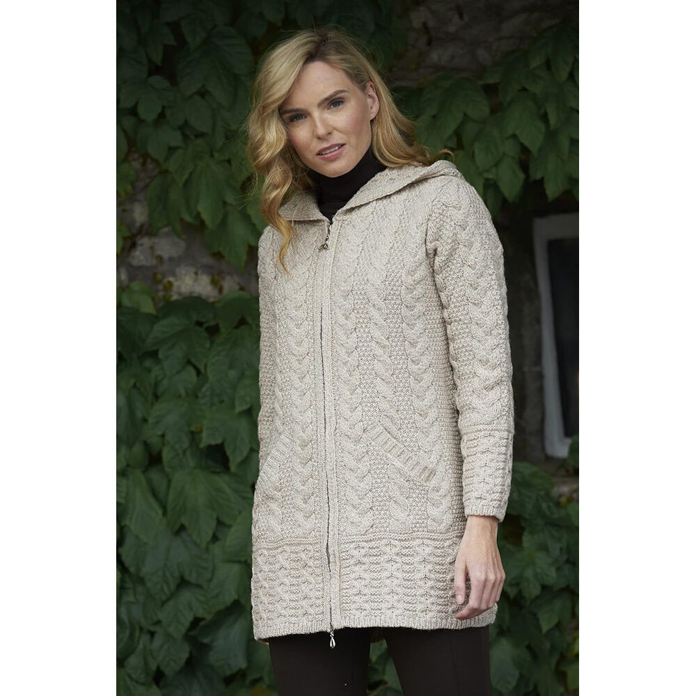 Woman wearing a beige knitted hooded cardigan standing outdoors