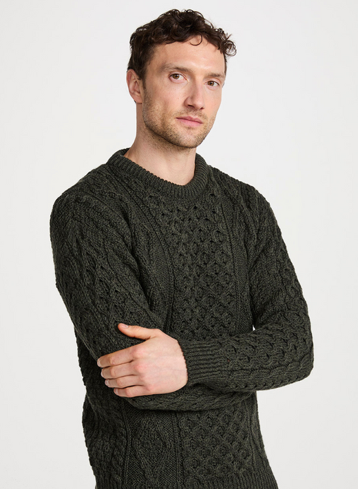 Close up of man wearing charcoal crewneck Aran wool sweater with intricate knit pattern