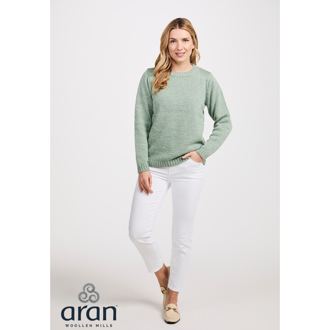 Full length shot of a woman in a mint green Aran Supersoft Crew Neck Sweater with white pants in a studio