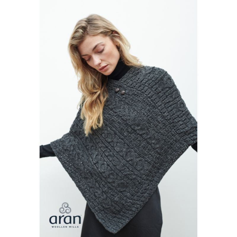 Woman wearing a dark gray textured knitted poncho with buttons