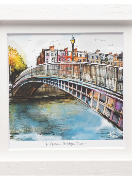 Watercolor illustration of Ha'penny Bridge in Dublin over a river with colorful houses in the background, framed in white.