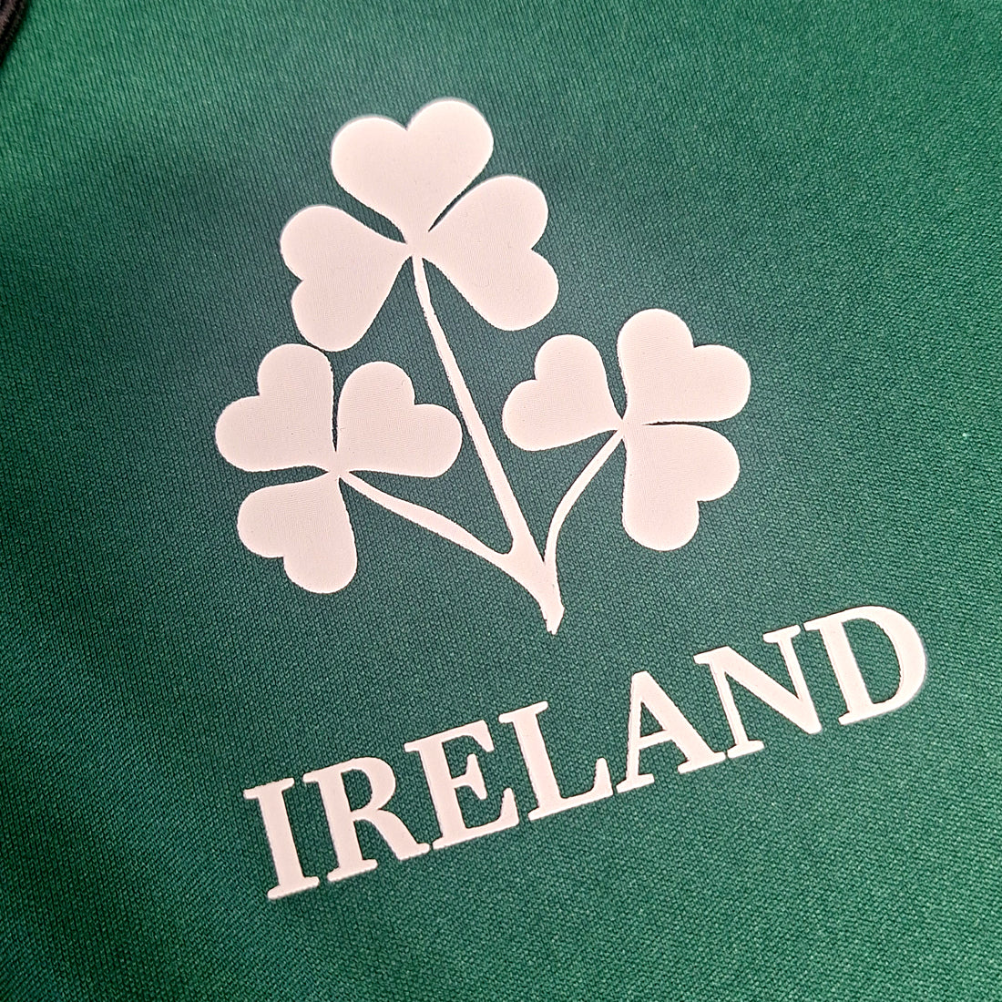 White shamrock emblem on textured green polo fabric