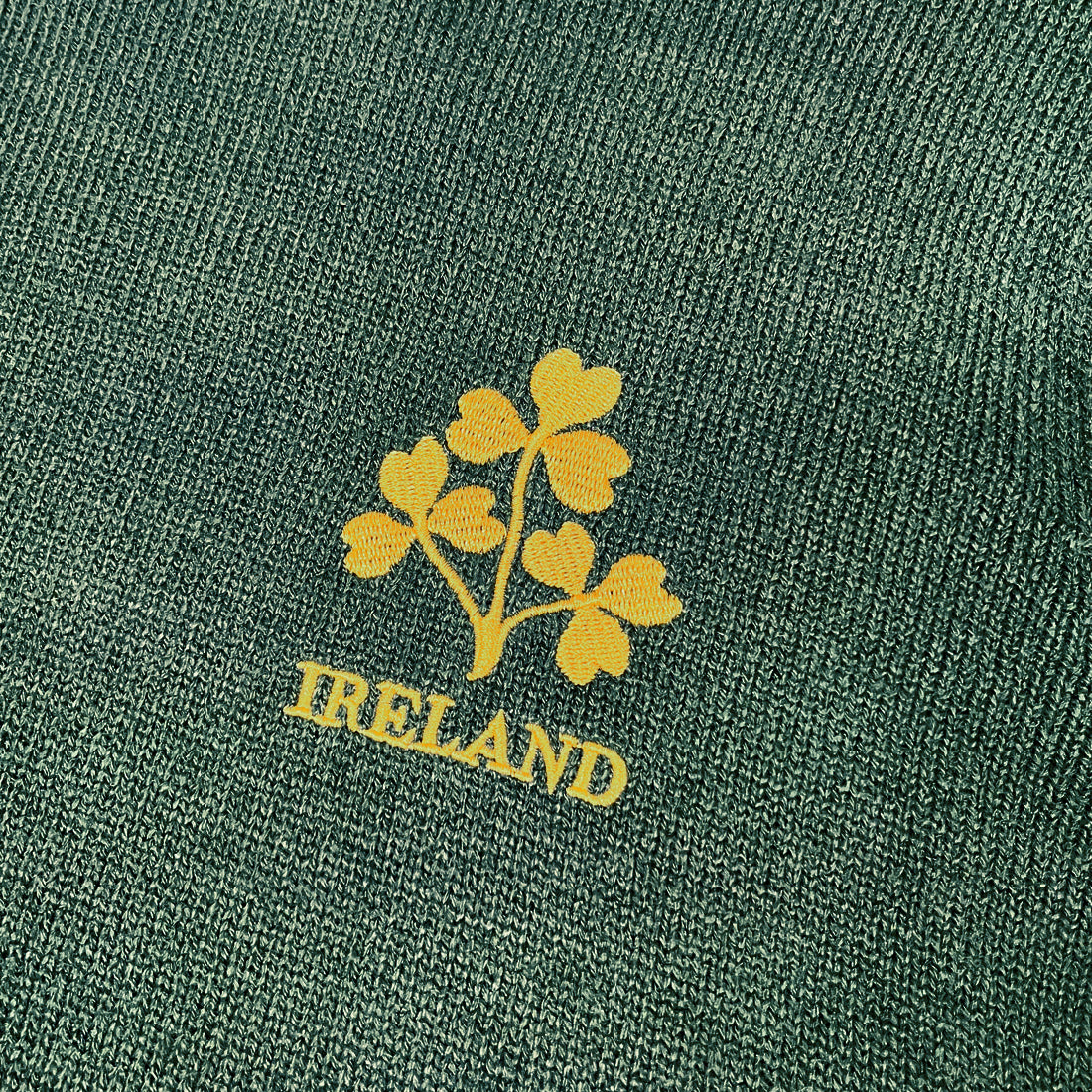 Close-up of bottle green knit fabric with a yellow shamrock bouquet and IRELAND text.