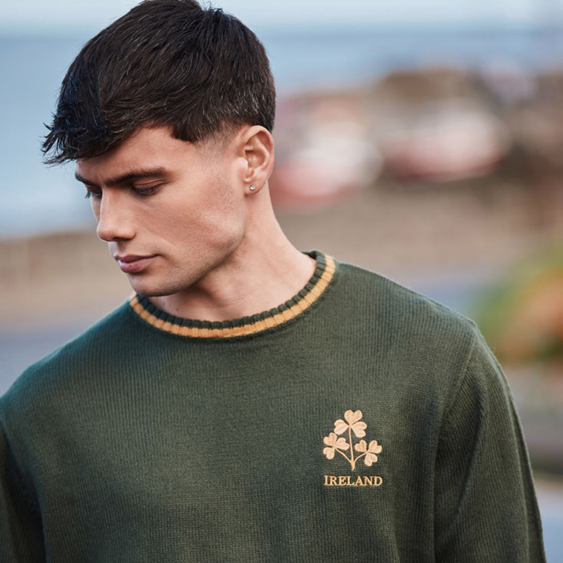 Male model wearing bottle green three shamrock crew neck jumper with gold left chest embroidery.