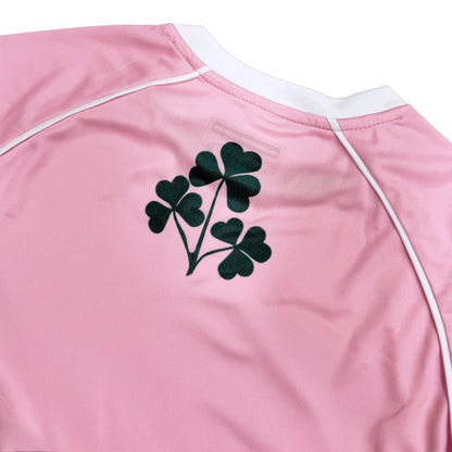 Back view of pink Lansdowne Ireland kids performance top with a dark green clover graphic.