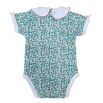 White baby vest with an all over green shamrock and pink floral print and a white collar
