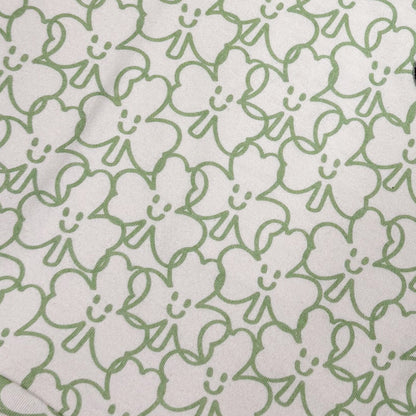 Fabric close-up showing white background with green shamrock outline print used on the dress