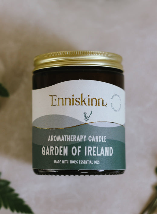 Aromatherapy candle labeled Garden of Ireland with gold lid and green leaves