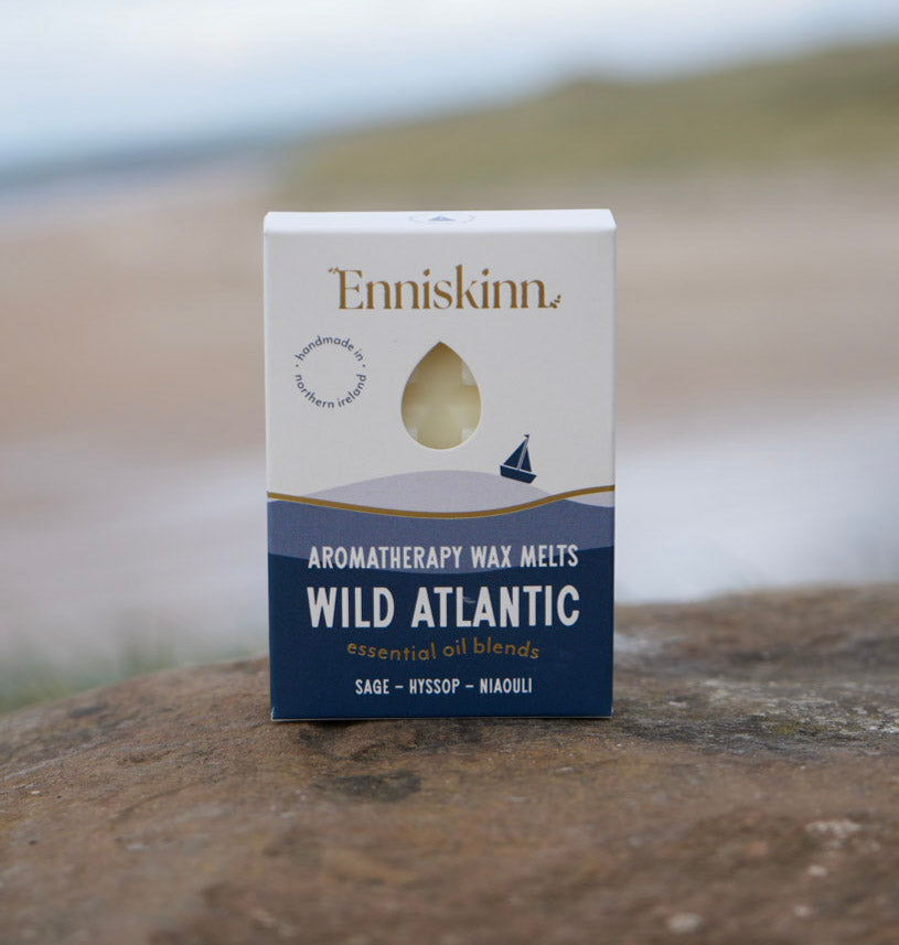 Enniskinn Wild Atlantic Aromatherapy Wax Melts box on a rocky seaside surface with blurred ocean in the background.