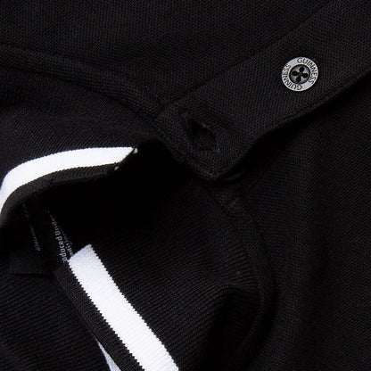 Close up of black Guinness polo showing a metallic crest button and white striped collar