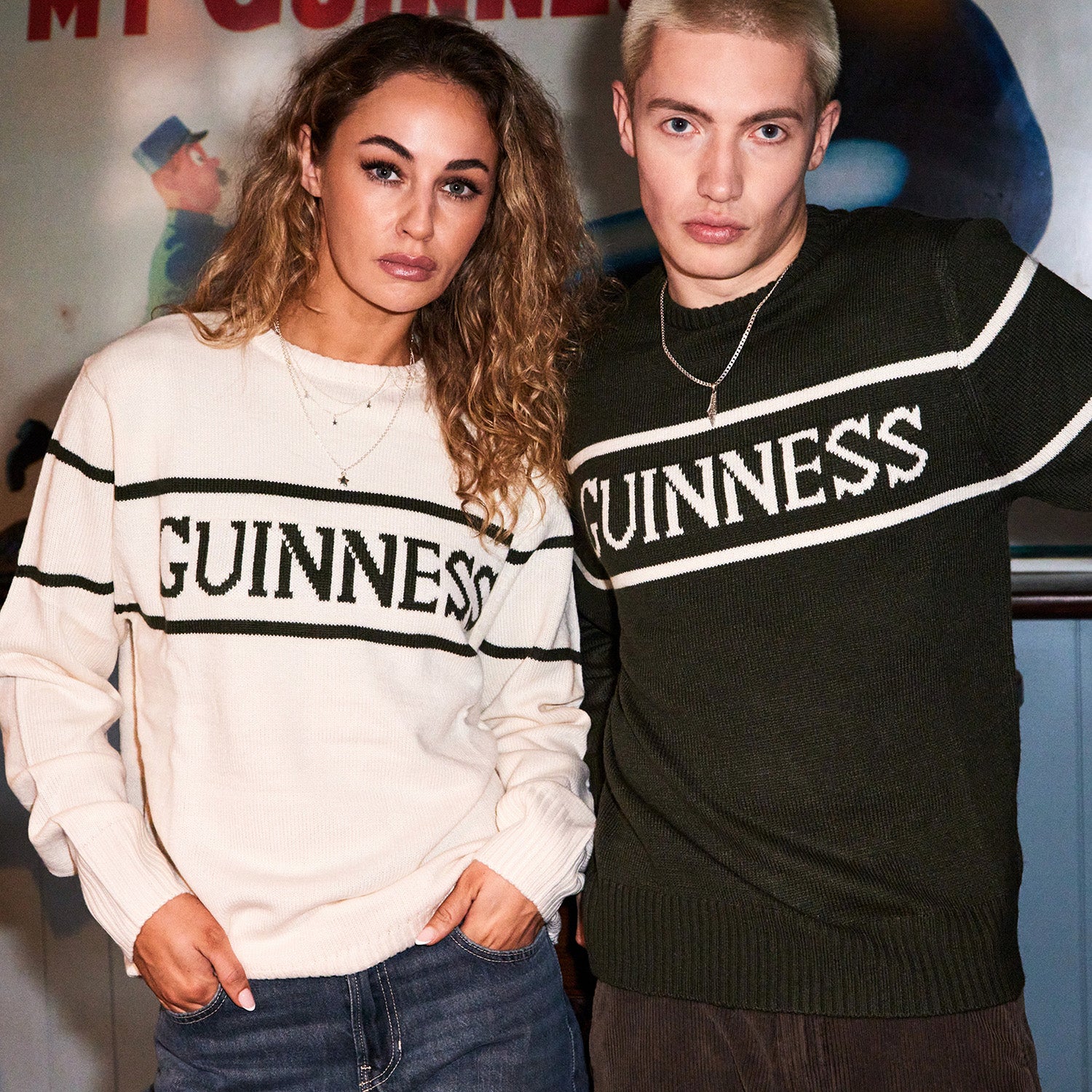 Two models wear Guinness knit sweaters cream and dark green with bold GUINNESS lettering across the chest.