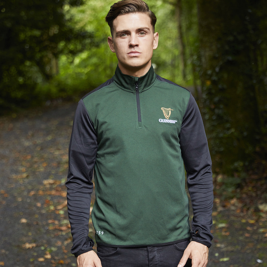 Male model wearing Guinness 1759 quarter zip top in green with black sleeves outdoors